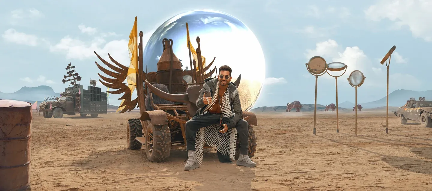 WE campaign scene with a man seated beside a reflective spherical structure in a desert