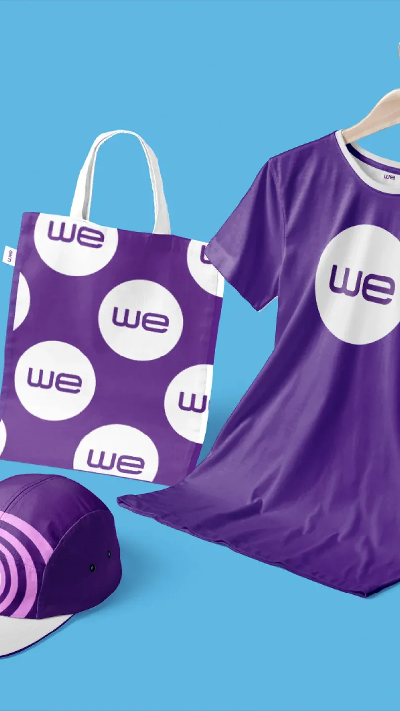 WE branded purple clothing, cap and patterned tote bag on cyan