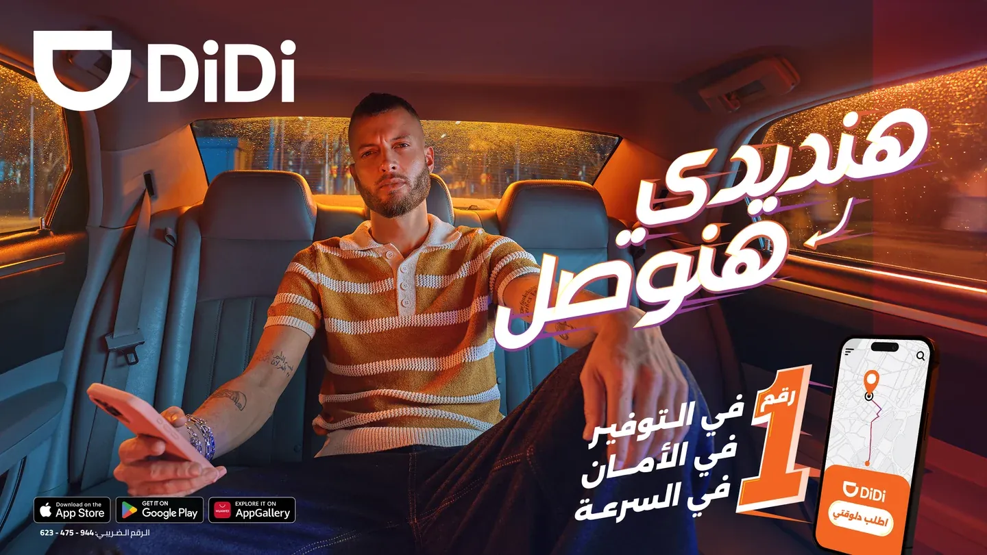 DiDi real campaign artwork with a man seated in a car, white Arabic lettering and phone screen