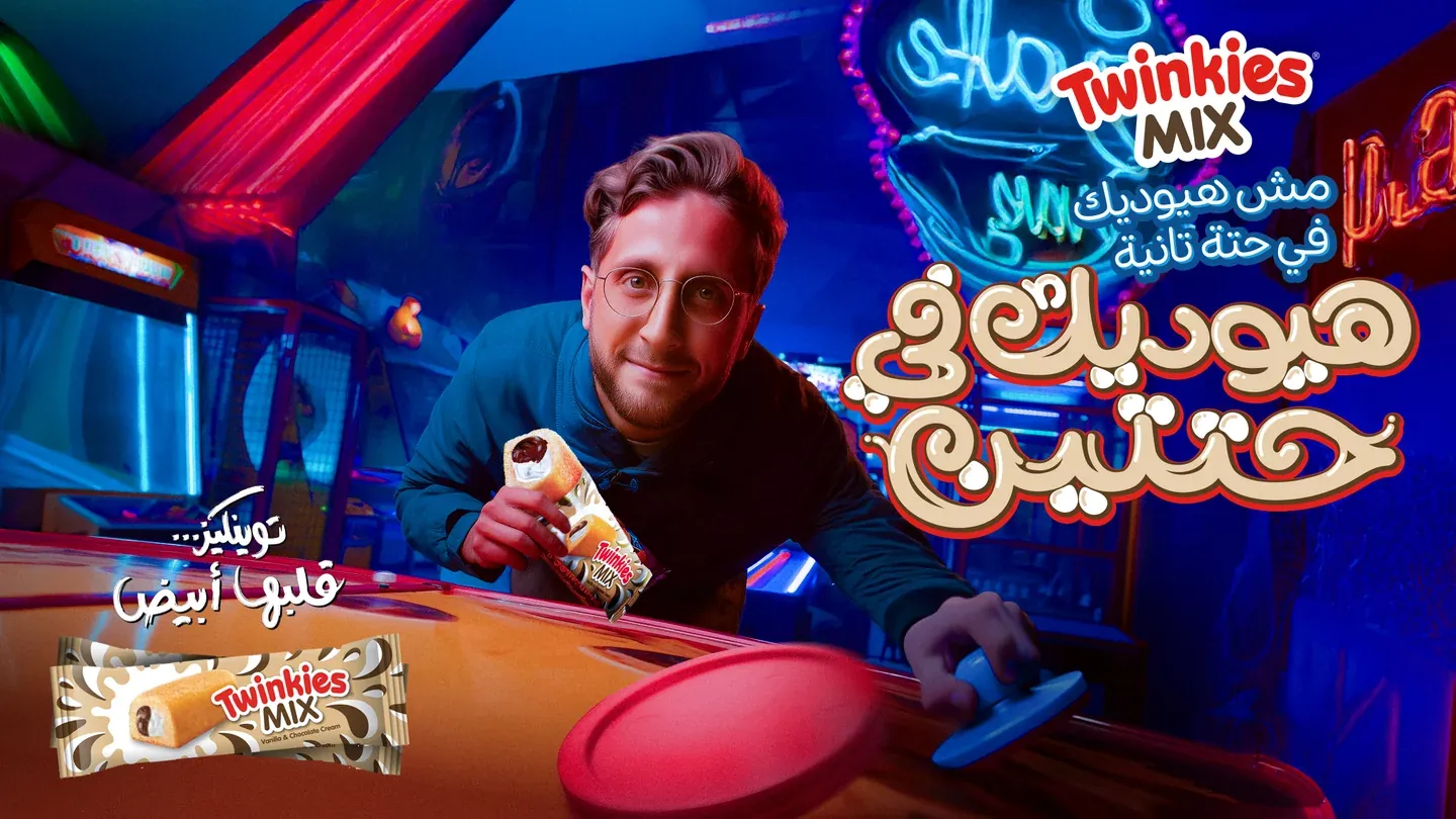 Twinkies Mix artwork with a man holding a cake in a colourful neon-lit amusement setting