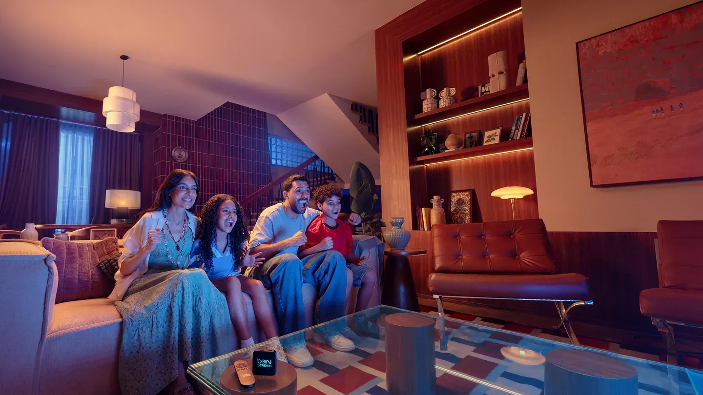 A family cheering together on a sofa in a warmly lit living room