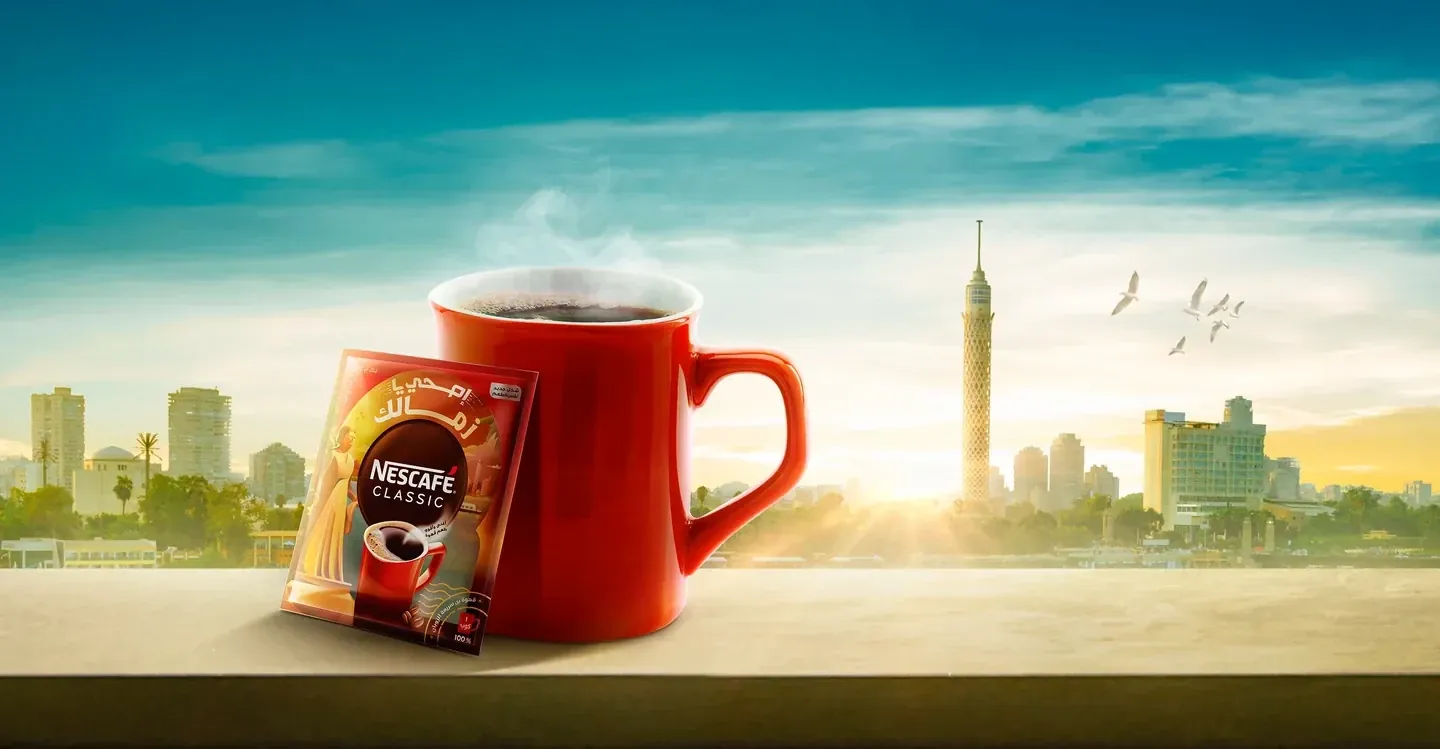 Nescafé Classic red mug and coffee pack overlooking the Cairo skyline under a turquoise sky